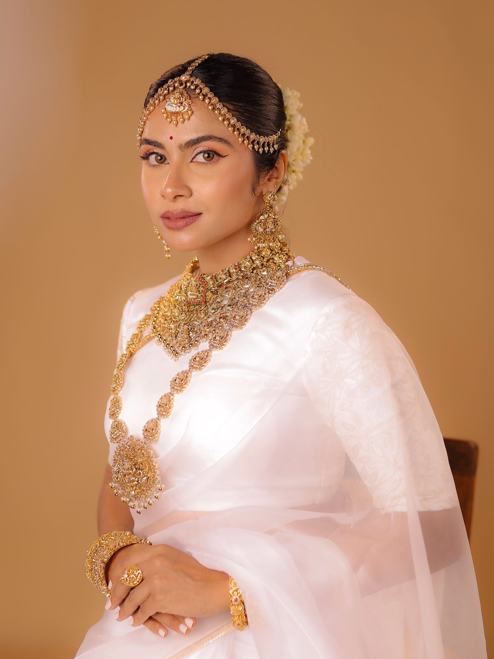 Maria, a Christian Kerala bride in white kasavu wearing a heavy gold temple long-haram from Golden Cup