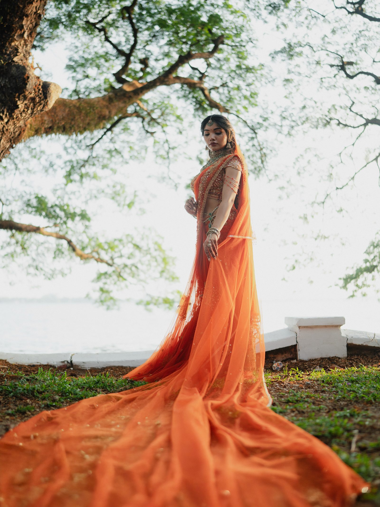 Reshma standing under a tree in her bridal saffron